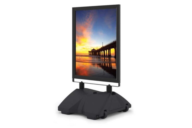 Black sidewalk sign with sunset image.
