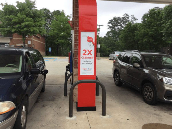 Two cars at a gas station with sign.